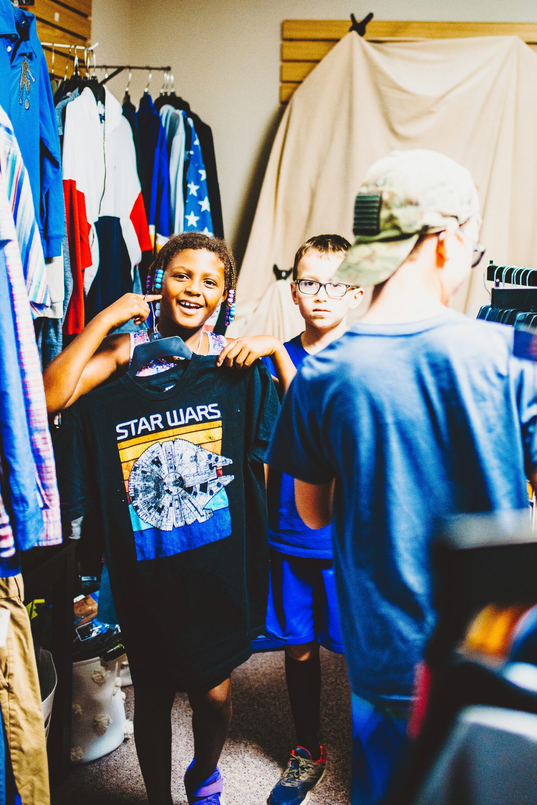 young girl smiling and holding tshirt in foster closet